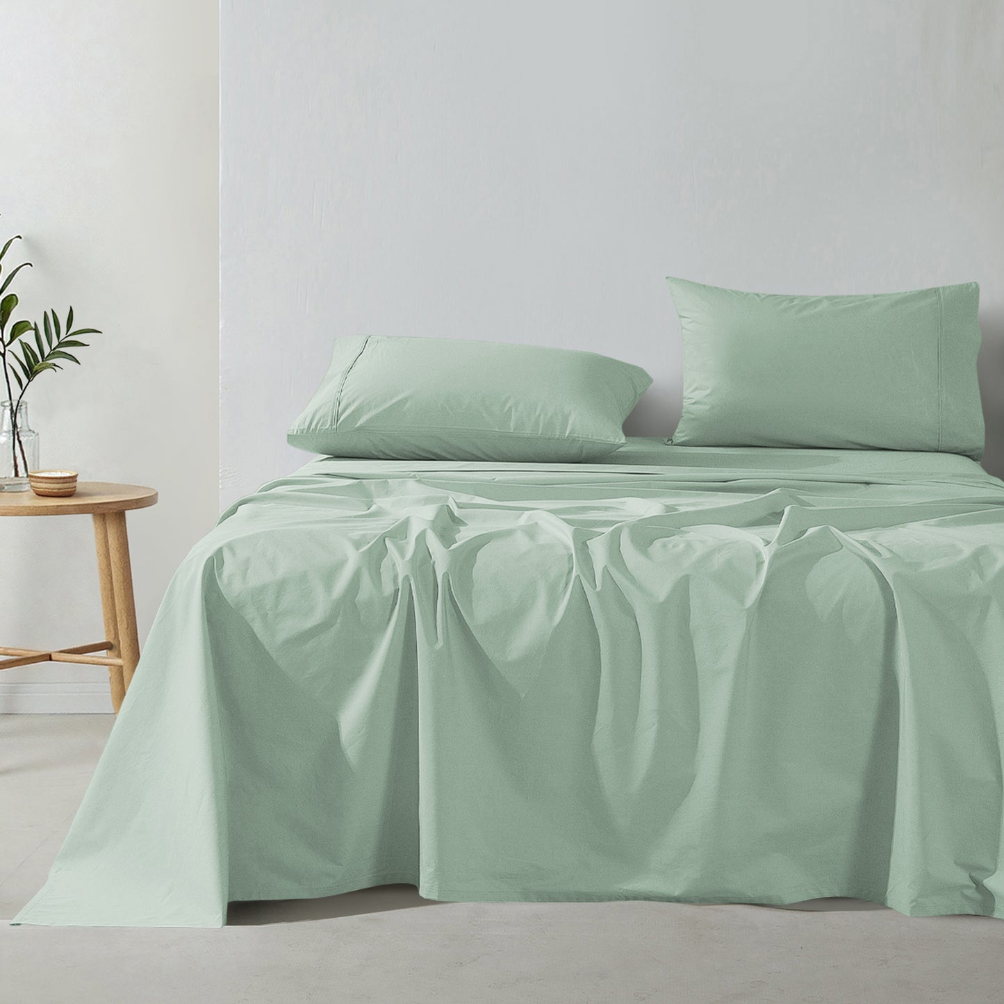 sage green cotton percale sheet set on bed with pillows